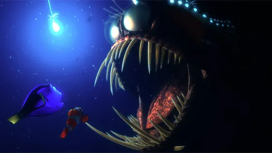 A scene from an animated movie showing a small clownfish and a blue tang fish encountering a large, menacing anglerfish in the ocean depths.