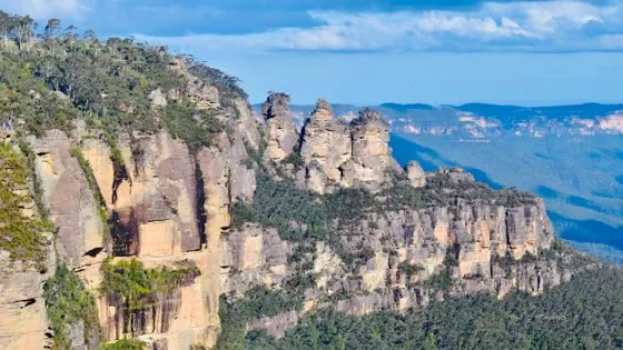 A panoramic view of the Three Sisters rock formation in the Blue Mountains under a clear sky.