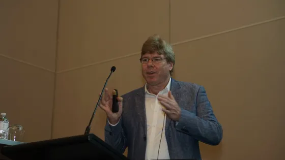 A man is giving a presentation at a podium in a conference room.