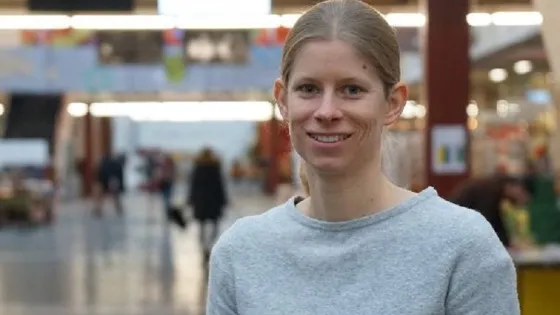 A woman smiling in a busy shopping center.