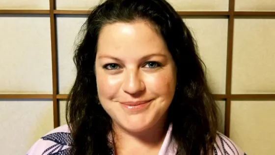 A woman smiling at the camera with a traditional Japanese sliding door background.