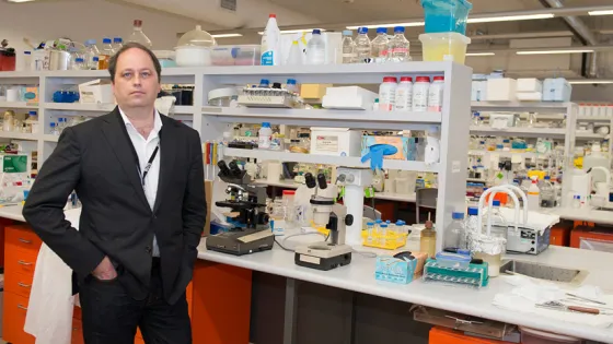 A man standing confidently in a lab coat inside a well-equipped laboratory.