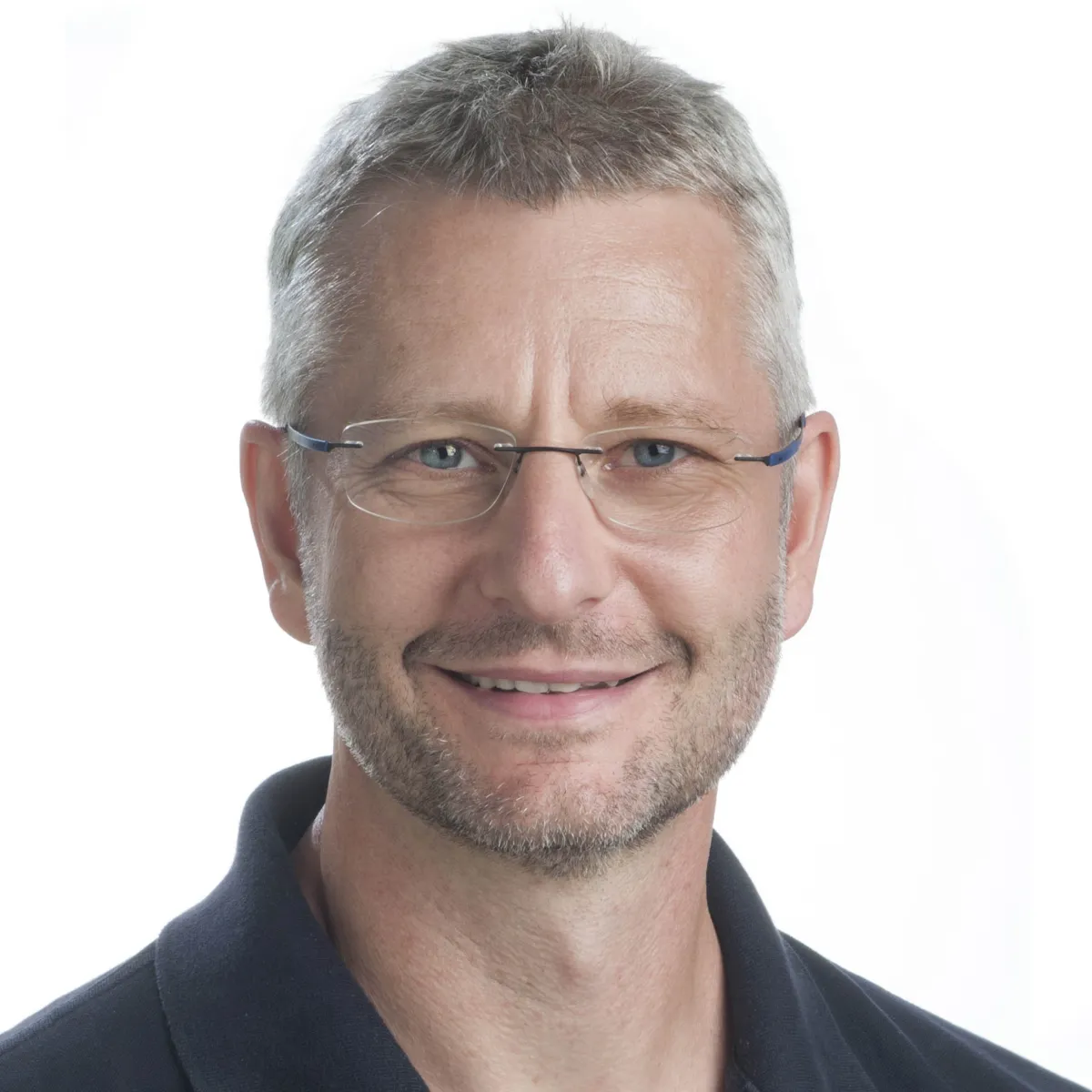 Portrait of a smiling middle-aged man with glasses, short gray hair, and a black shirt.