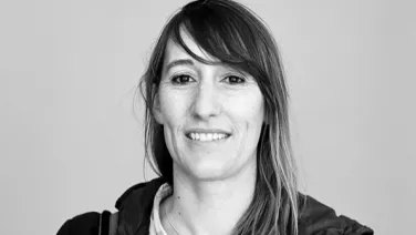 A black and white portrait of a smiling woman with shoulder-length hair.
